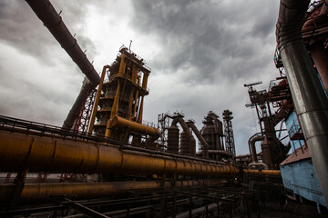 Fototapeta na wymiar Modern smelter. Rust blast furnace and tubes. Dark grey stormy clouds.