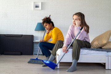 Tired multiethnic teenage children are bored while do household and domestic chores at home.