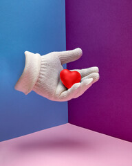 A hand in a white glove holds a red heart. Hand gesture. Care, love, support, concept.
