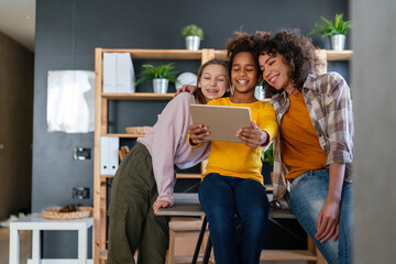 Group of teenage friend girls are using gadgets, talking and smiling together.