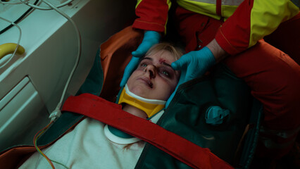 Close Up Shot of a Teenage Caucasian Girl Face Covered in Bruises and Blood After She Survived a Car Accident, Laying in a Stretcher With a Neck Brace As The Paramedic Holds Her Head.