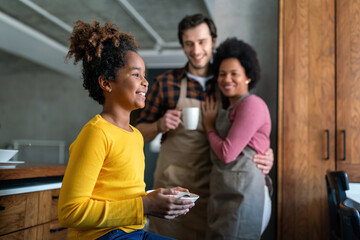 Overjoyed young multiethnic family with daughter having fun in kitchen together