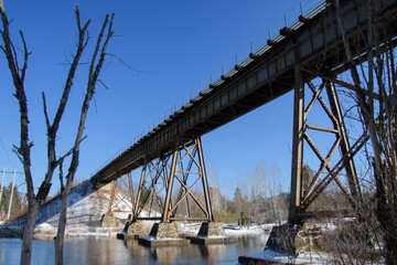Railway bridge over calm river in winter in Quebec, Canada