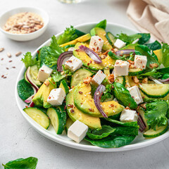 Vegetarian salad with vegetables, feta and seeds on a gray background.