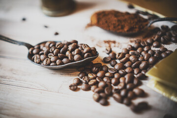 Top view of three different varieties of coffee beans on light wooden background