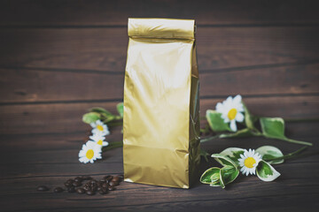 Mock-up golden metallic paper pouch bag on dark wooden table lying at coffee beans