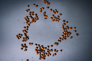 Heart shape made from coffee beans on wooden surface.