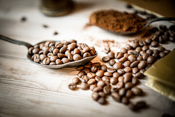 Group of high quality roasted coffee beans, spilled on wooden table. Brown-black shiny whole grains of coffee View from above. - obrazy, fototapety, plakaty