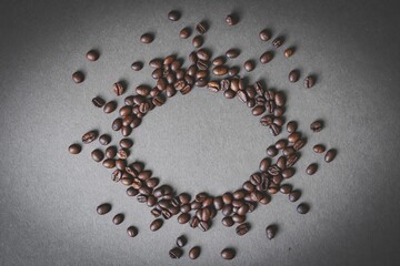 Cafes and restaurants. A mug of invigorating, black coffee and coffee beans in the shape of a heart on a dark gray background. Copy space for text. The concept of hot drinks and love.