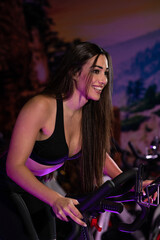 Fototapeta na wymiar Guapa mujer caucásica haciendo deporte con una bicicleta en el gimnasio