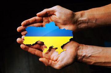 Support for Ukraine in the war with Russia. Hands holding the flag of Ukraine in the shape of the...
