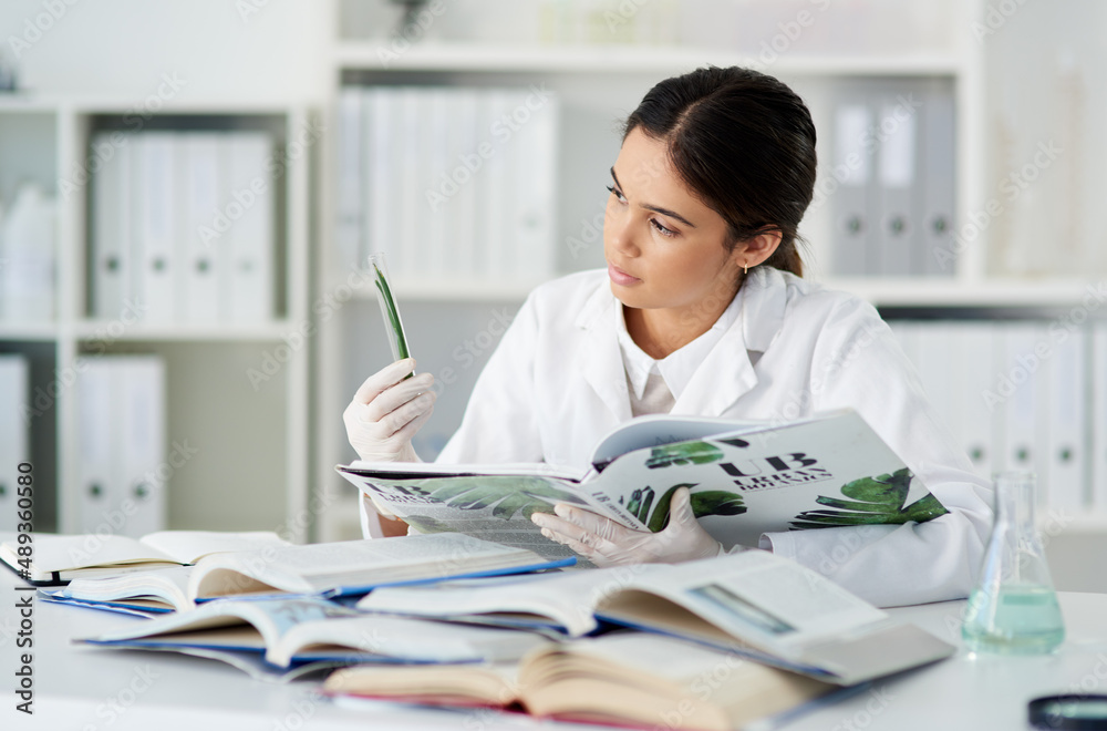 Aufkleber ive read about this plant before. shot of a young scientist reading a book while working with plant 
