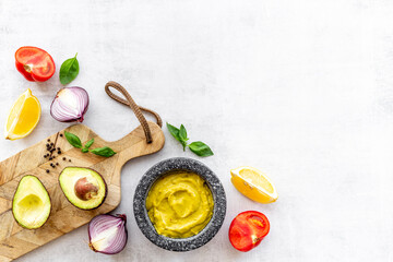 Mexican spicy guacamole avocado dip in mortar with ingredients