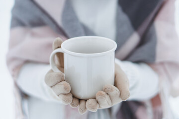 Young cute swarthy brunette woman drinking coffee from papper cup in snowy winter forest
