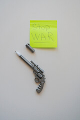 a pen in the form of a pistol lies on a table on a white background. Near the sticker "no war"