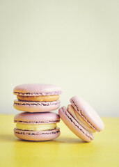 Three violet macarons on light background. Vertical photo. Delicious macaroons.
