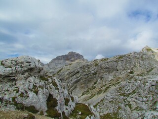 Rocky high alpine landscape with patches of grass and mountain Razor in Triglav national park and Julian alps at Kriski podi in Slovenia