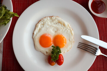 Fried eggs with cherry tomatoes in a white plate - Healthy breakfast at top view