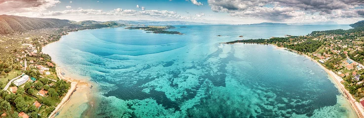 Foto auf Glas Aerial panoramic scenic view of azure blue lagoon and paradise bay with majestic patterns on a sea shelf. Resort village of Vourvourou on Sithonia peninsula in Halkidiki, Greece © EdNurg