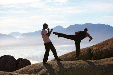 Training in the mountains. Two male kickboxers training on a mountain top.