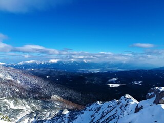 Obraz premium Scenic view of snow covered Gorenjska region of Slovenia in winter with the Karavanke mountains in the back and forested Pokljuka plateau in front