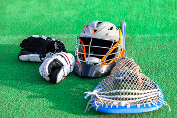 Lacrosse gear laying on the grass field, american sports themed photograph.