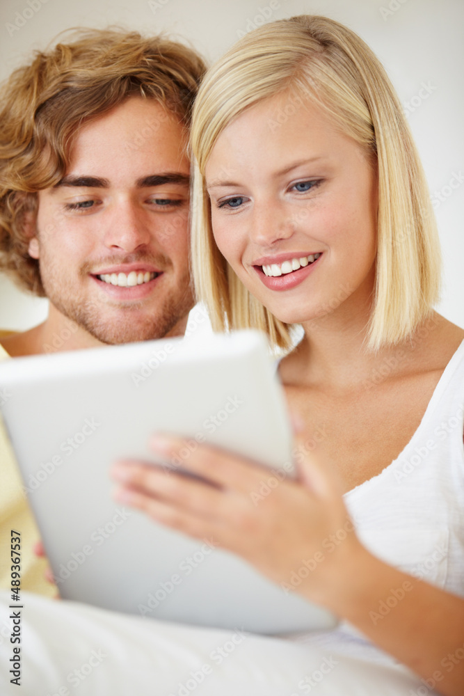 Poster User intuitive. A young couple browsing the internet on their tablet from the comfort of their couch.