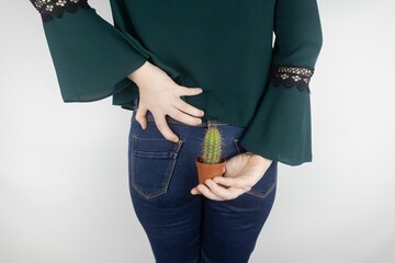 Concept. A woman holds a cactus as a symbol of rectal pain. Varicose veins of the lower intestine....