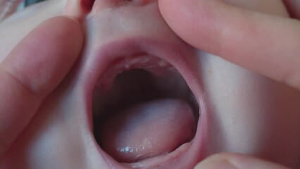 Baby care. Mom examines the mouth and gums of the child. Mom checks if the first teeth of the child have erupted.