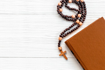 Bible book with wooden christian rosary beads with cross