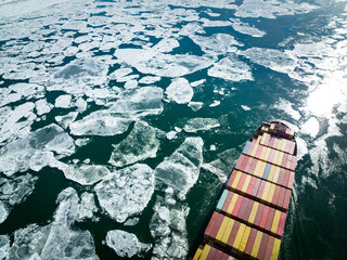 Aerial view of a container ship going upstream through winter ice in the St. Lawrence River near the port of Montreal in Canada