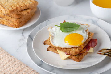 Sandwich with a fried egg, bacon, cheese and spinach