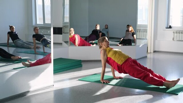 Old woman yoga teacher doing  class with female group in studio 