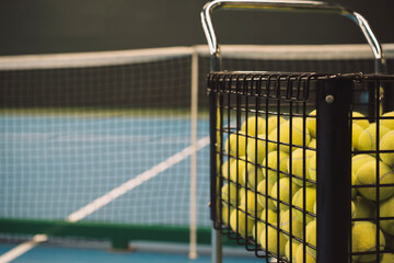 Obraz premium cart with yellow tennis balls on tennis court with blurred background