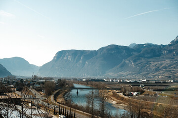 Beautiful view of the river near a bridge with mountains background in Bolzano, Italy - obrazy, fototapety, plakaty