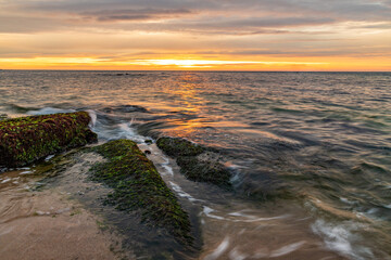 Obraz premium Seascape view of a calm sea with rocks with moss. Beauty sky with clouds at the horizon.