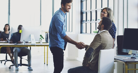 Lets get to work. Cropped shot of two businessmen shaking hands while working in their office.