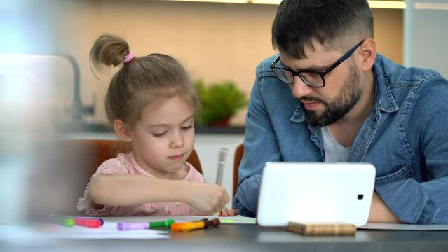 Close up of father and little child learn to draw watching drawing lesson on internet at home. Online education concept. Video tutorial, drawing training.