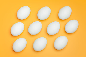 Pattern from white chicken eggs on yellow background top view. Creative food minimalistic background.