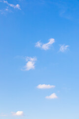 Blue sky with small white clouds in vertical alignment.