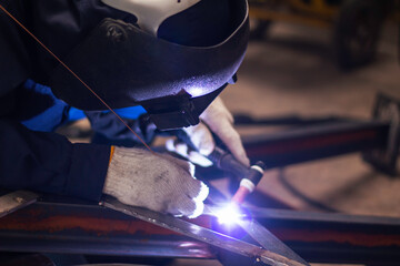 welder Industrial automotive part in factory. Workers wearing industrial uniforms and welding masks...