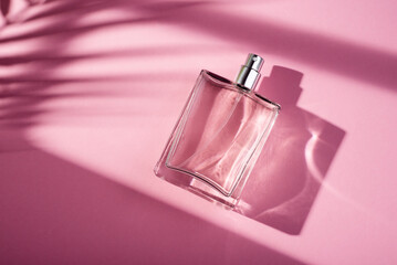 Transparent bottle of perfume on a pink background. Fragrance presentation with daylight.