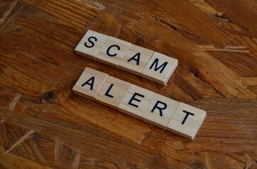 scam alert text on wooden square, motivation and business quote