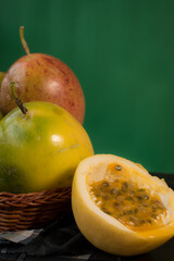 Naklejka na ściany i meble Passion fruit in a basket on a black wooden table with green background 