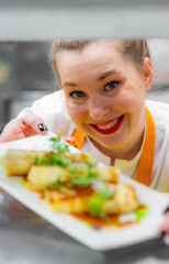 Portrait of woman chef with plate of food on kitchen