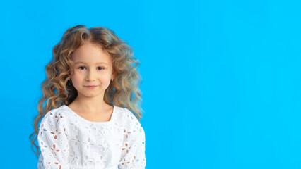 portrait little beautiful cute blonde girl with curls on blue background. children for peace, against war. peaceful sky. banner, copy space, text