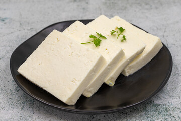 Sliced Feta cheese with herbs on stone background. Close-up breakfast cheese