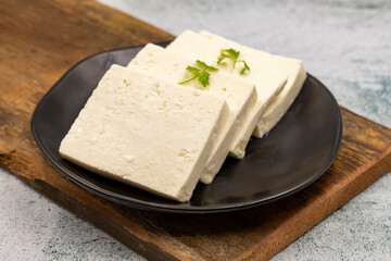 Sliced Feta cheese with herbs on stone background. Close-up breakfast cheese