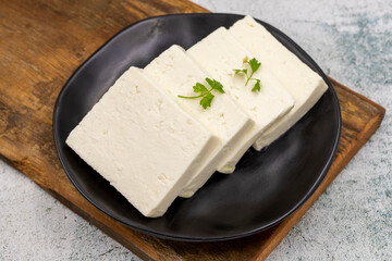 Sliced Feta cheese with herbs on stone background. Close-up breakfast cheese