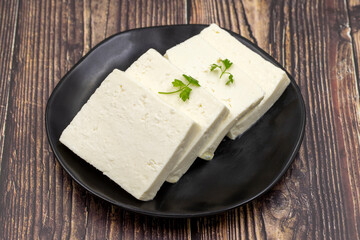 Sliced Feta cheese with herbs on wooden background. Close-up breakfast cheese